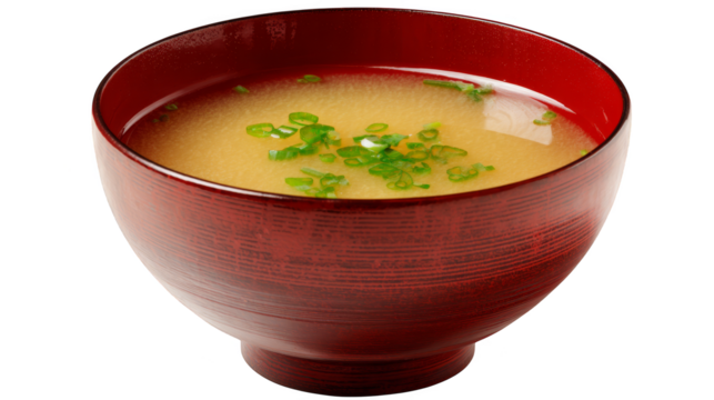 Steaming hot soup with fresh green onions in a vibrant red bowl.