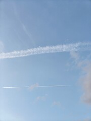 airplane in the skyThe evening sky was clear blue with white clouds in horizontal and lumpy stripes.