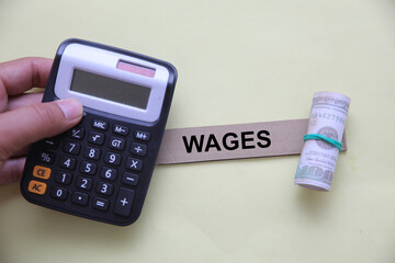 WAGES Concept with Hand Holding Sign, Calculator, and Rolled Dollar Bills – Economic and Labor Cost Theme