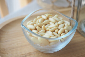 Freshly harvested pine nuts in a glass bowl on a wooden tray