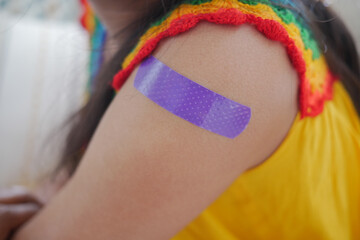 Child with colorful bandage on arm in bright clothing