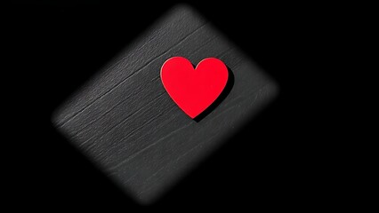 Obraz premium Red heart-shaped object on a dark textured surface, conveying emotion through minimalist design.