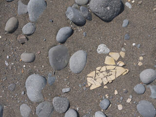 Fragments of ancient pottery weathered from the sand on Ainu settlement archeological site on Iturup, Kuril Islands