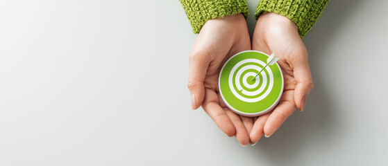 Hands holding green target icon with arrow symbolizing goals