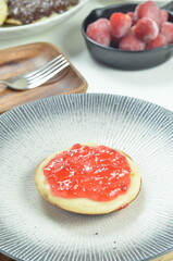 Serabi pancakes topped with strawberry jam, a traditional Indonesian snack