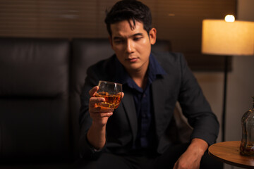 Businessman holding a glass of whiskey in a restaurant sitting on a sofa