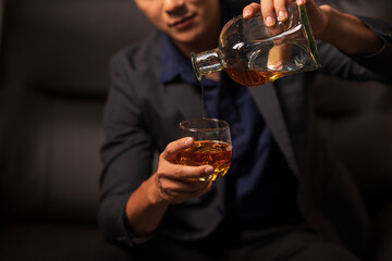 Businessman holding a glass of whiskey in a restaurant sitting on a sofa