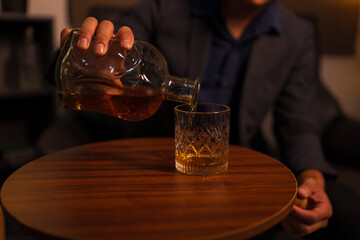 Businessman holding a glass of whiskey in a restaurant sitting on a sofa