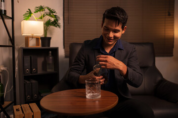 Businessman holding a glass of whiskey in a restaurant sitting on a sofa