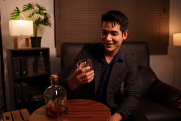 Businessman holding a glass of whiskey in a restaurant sitting on a sofa