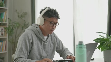 Asian man uploads video files from a digital camera and begins editing the footage on his laptop.4k