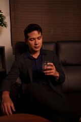 Businessman holding a glass of whiskey in a restaurant sitting on a sofa