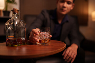 Businessman holding a glass of whiskey in a restaurant sitting on a sofa
