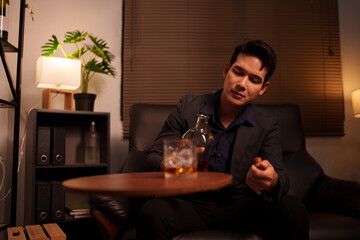 Businessman holding a glass of whiskey in a restaurant sitting on a sofa