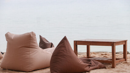  Bean bags and tables are placed on the beach facing the sea