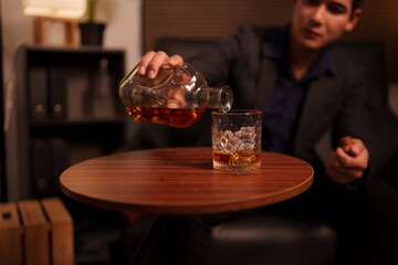 Businessman holding a glass of whiskey in a restaurant sitting on a sofa