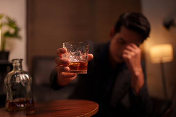 Businessman holding a glass of whiskey in a restaurant sitting on a sofa