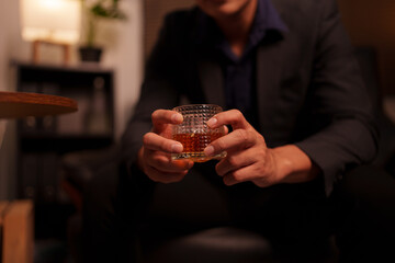 Businessman holding a glass of whiskey in a restaurant sitting on a sofa