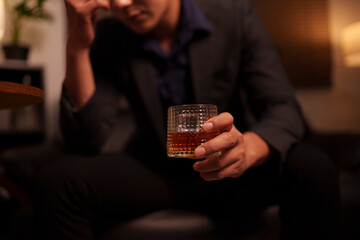 Businessman holding a glass of whiskey in a restaurant sitting on a sofa