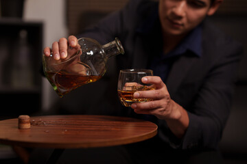 Businessman holding a glass of whiskey in a restaurant sitting on a sofa
