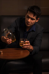 Businessman holding a glass of whiskey in a restaurant sitting on a sofa
