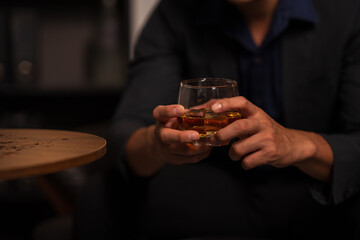 Businessman holding a glass of whiskey in a restaurant sitting on a sofa