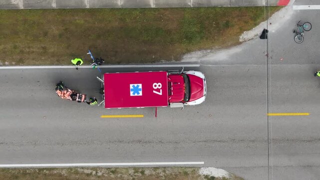 Car accident with pedestrian casualty on paramedics stretcher on highway road in Florida. Emergency services helping victim of vehicle hit on city street in USA.