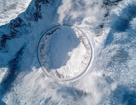 Aerial view of a circular road winding through snow-covered mountains