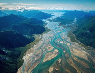 Aerial view of a braided river carving through a lush mountain valley