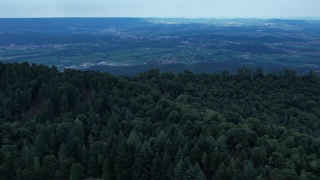 Drone panorama of the Ivrea Morainic Amphitheatre seen from Brosso, Val Chiusella, Italy, showing lush green plains, woods, and scattered villages under clear sky, high drone shot, slow motion