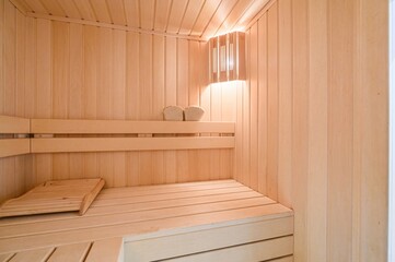 serene sauna interior featuring wooden benches and wall panels, illuminated by a warm light fixture