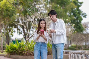 Fototapeta premium Asian Couple Exchanging Gifts Outdoors