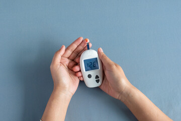 Woman's hands checking diabetes and hyperglycemia with digital blood sugar meter. Healthcare and...