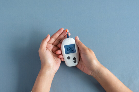 Woman's hands checking diabetes and hyperglycemia with digital blood sugar meter. Healthcare and medical concept	
