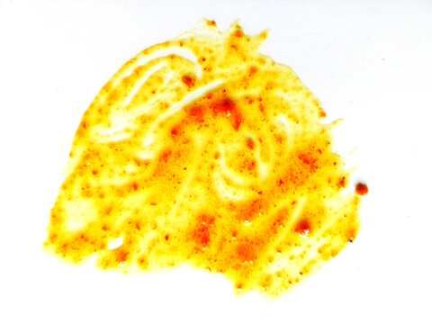 Yellow oil stains mixed with red sauce and food residue. Greasy stains after a meal on a white background