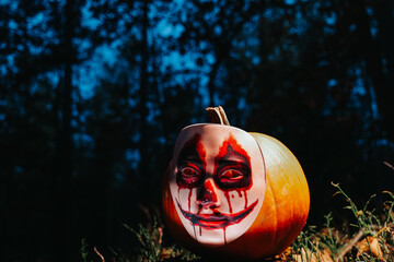 Scary Mask Look.halloween Mask on Pumpkin. Scary pumpkin in the dark forest.Halloween wallpaper with a scary pumpkin