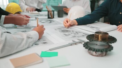 A diverse group of engineers and architects engage in a collaborative session, reviewing technical drawings and using tools in a bright and organized office setting. SACTR