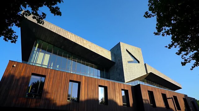 Modern Wood and Glass Building Exterior Under a Clear Blue Sky Framed by Trees
