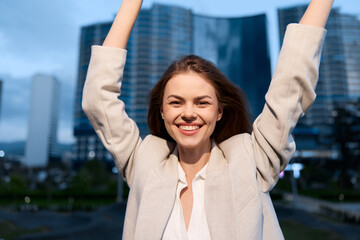 Happy businesswoman celebrating success outdoors in a modern urban setting, showcasing confidence...
