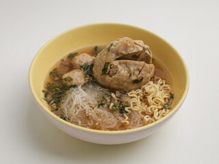 Chicken noodles and meatballs soup in white bowl 