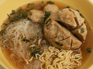 Chicken noodles and meatballs soup in white bowl 