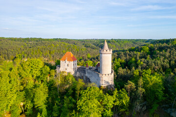 Kokorin Castle stands majestically amid lush greenery during a sunny evening in Czechia. The aerial...