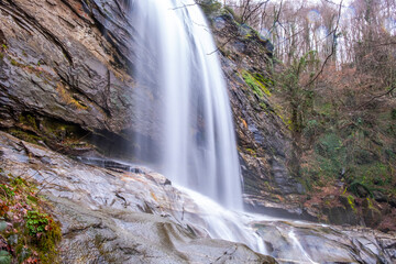 A serene view of Suu&ccedil;tu Waterfall in Bursa, with water cascading over moss-covered rocks, surrounded by lush greenery and trees, creating a peaceful, natural landscape perfect for nature lovers.