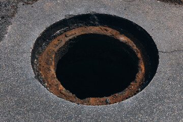 Workplace on a city street, road surface repair and installation of a manhole cover. Close-up with a prepared hole. The picture highlights the stages of work to maintain the city infrastructure.