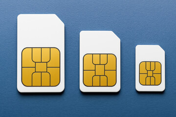 Three White SIM Cards of Varying Sizes on a Blue Surface Representing Mobile Technology and Connectivity