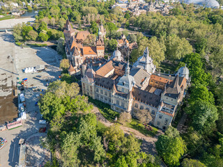 Morning drone photo of Vajdahunyad Castle centered in Budapest’s City Park, showcasing detailed architecture and moat from an aerial perspective in soft natural light.  