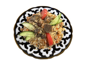 A serving of pilaf garnished with cucumbers and tomatoes on a traditional plate