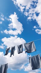 Promote sustainable living with airy outdoor laundry imagery gray garments dancing on a sunlit clothesline under blue skies. Ideal for eco-friendly brands, home decor, and fashion marketing.