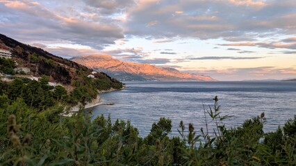beautiful coastal landscape sunset scenery, natural rock formations at sandy paradise beach, with mountain Biokovo in background, Mimice, Dalmatia, Croatia, Adriatic sea at Mediterranean