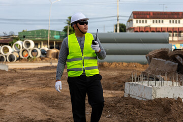 Civil engineer supervising the installation of concrete drainage pipes at a roadside construction site.
